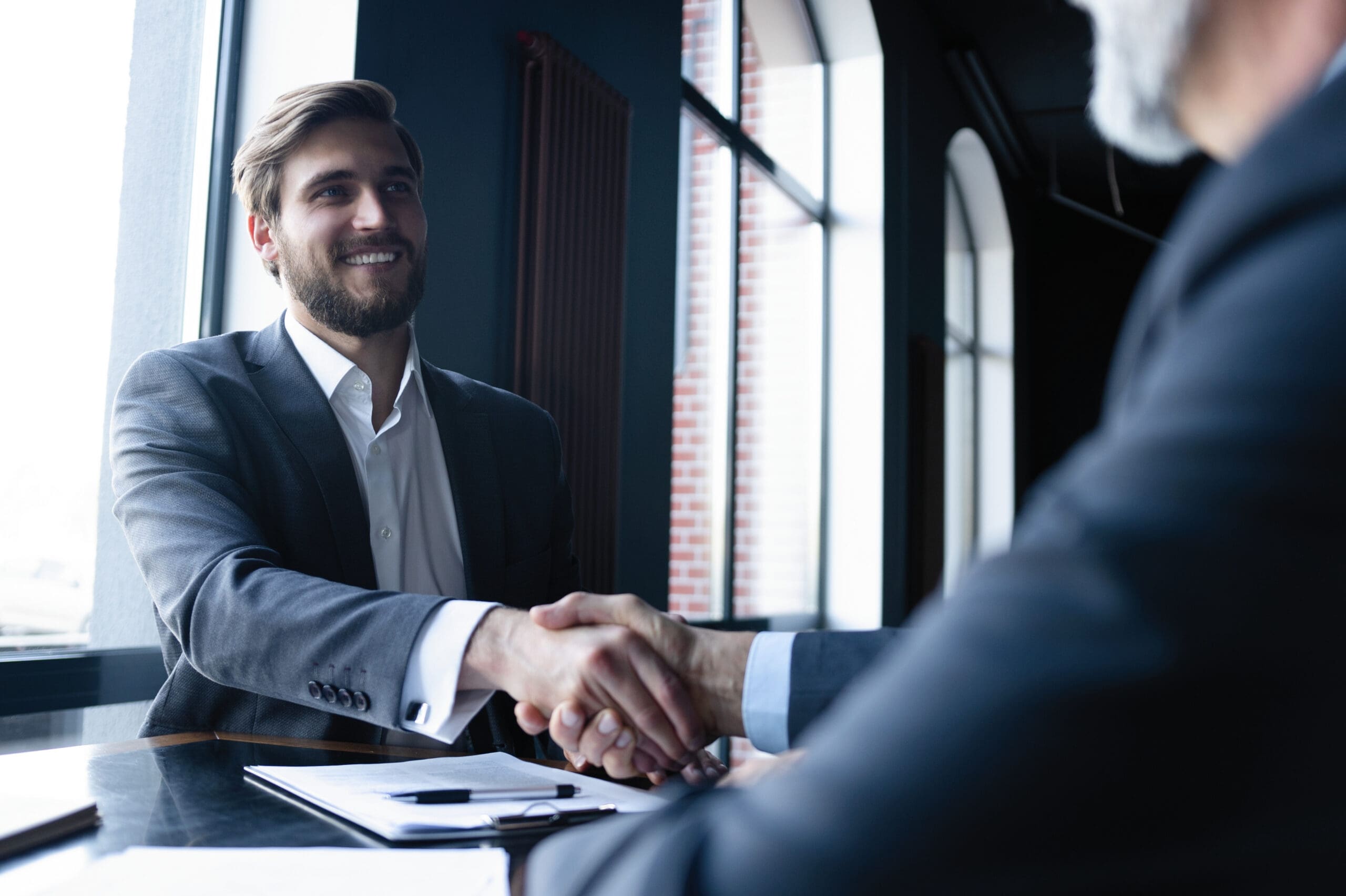 Good deal. Two business people shaking hands while sitting at the working place.